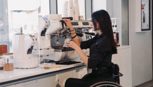 An image of a woman working in a cafe, she uses a wheelchair.